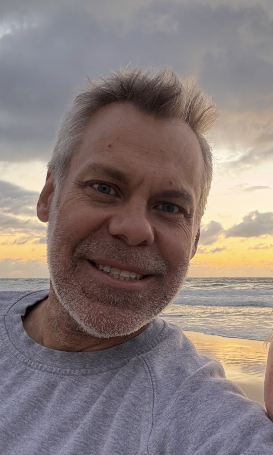 Marty Bate smiling on the beach at sunrise
